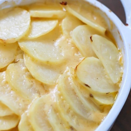 Cheesy Potatoes au Gratin made with a homemade cheese sauce drizzled over thinly sliced potatoes and a layer of onions nestled in the middle. A great Thanksgiving recipe! Plus a full blog hop Thanksgiving menu to help plan your turkey day meal!