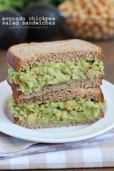 Avocado Chickpea Salad Sandwiches stacked on top of eathother on a white plate.