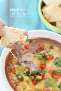 Pita chip is dipped into a cheesy Healthy Black Bean Dip + 43 Healthy Snack Ideas!