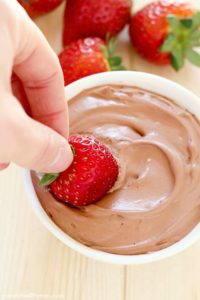 Bright red strawberry is dunked into a creamy Chocolate Yogurt Dip + 43 Healthy Snack Ideas