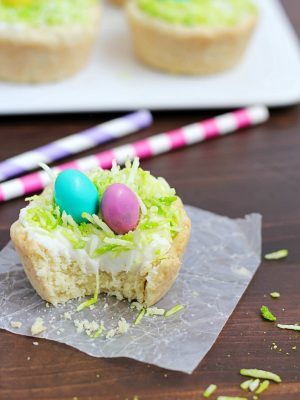 Need a fun treat to make for an Easter get together? Make these darling Easter Nest Sugar Cookie Cups! Sugar cookie dough cooked in a muffin tin, filled with vanilla frosting, topped with green tinted coconut and M&M eggs to look like a little bird's nest. So cute and great for spring! #truvia