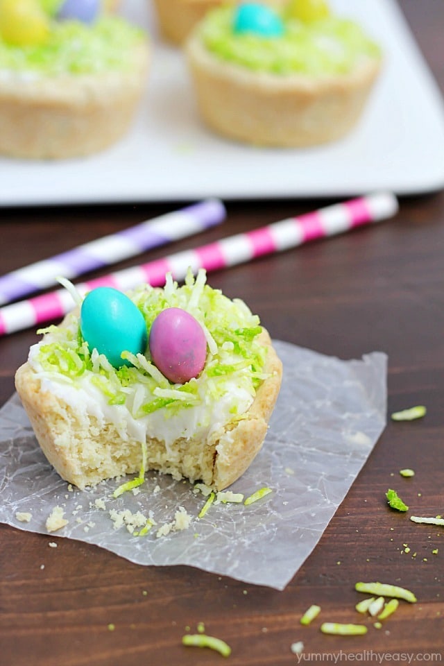 Need a fun treat to make for an Easter get together? Make these darling Easter Nest Sugar Cookie Cups! Sugar cookie dough cooked in a muffin tin, filled with vanilla frosting, topped with green tinted coconut and M&M eggs to look like a little bird's nest. So cute and great for spring! #truvia