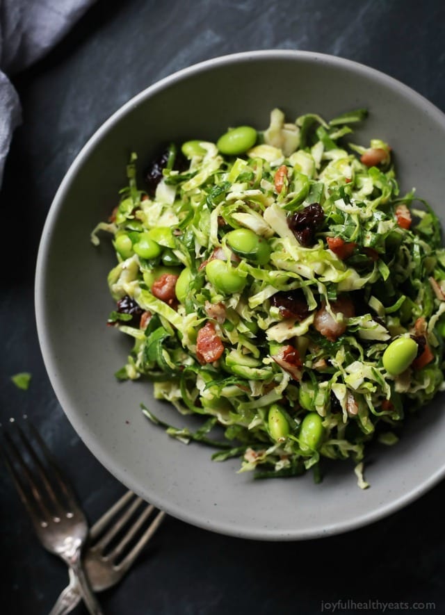 A light Autumn Kale & Shaved Brussel Sprout Salad infused with crispy bacon, edamame, and a surprise sweet fruit that compliments the dish perfectly. 