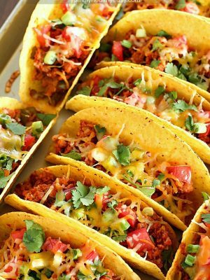 Ground Turkey Tacos that are oven-baked with layers of deliciousness inside! Refried beans, ground turkey taco meat, (no taco seasoning mix!) tomato, cilantro, green onions and cheese all baked in taco shells. Perfect for Taco Tuesday or for game day!