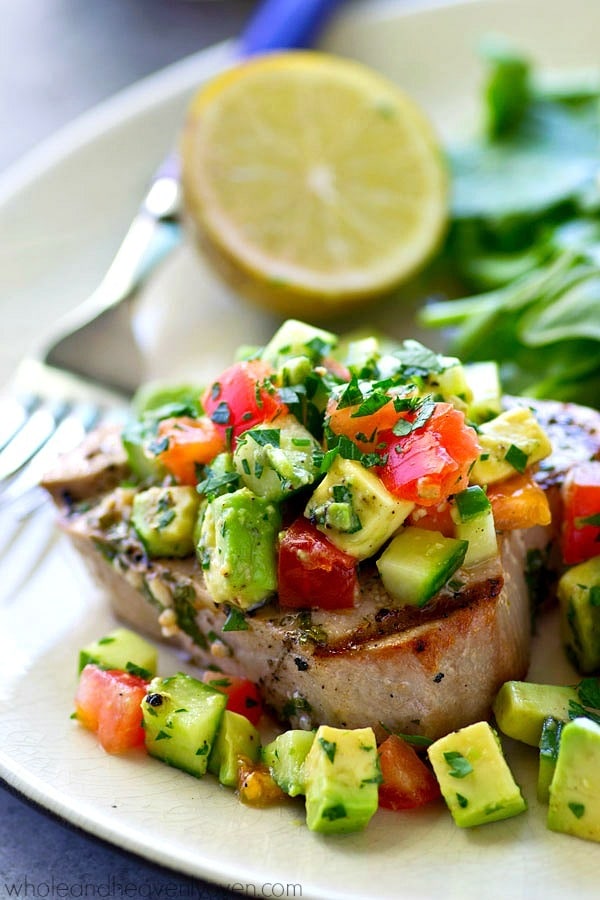 Tender tuna steaks are marinated in cilantro and lots of lime, grilled until perfectly smoky, and topped with an amazing fresh avocado cucumber salsa for one easy summer dinner! 