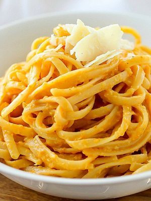 Creamy Pumpkin Pasta in a white bowl and topped with parmesan cheese.