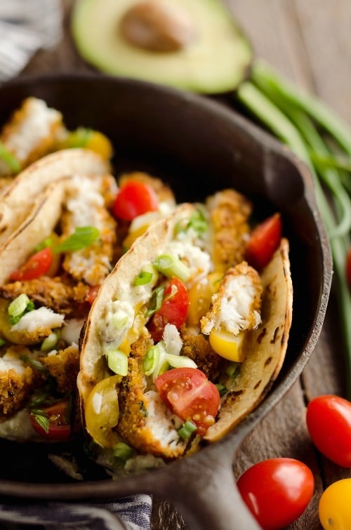Tortilla Crusted Fish Tacos with Avocado Crema are a healthy and easy weeknight meal you can make in just 20 minutes with your Airfryer! Crispy Tortilla Crusted Tilapia is layered in a grilled corn tortilla with avocado crema and fresh tomatoes for a flavorful dinner recipe the whole family will love.