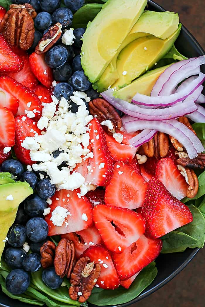 SO much flavor packed into one salad! This Spinach Salad Recipe is filled with leaves of spinach topped with berries, avocado, feta cheese, walnuts and a homemade honey-garlic vinaigrette! #ad