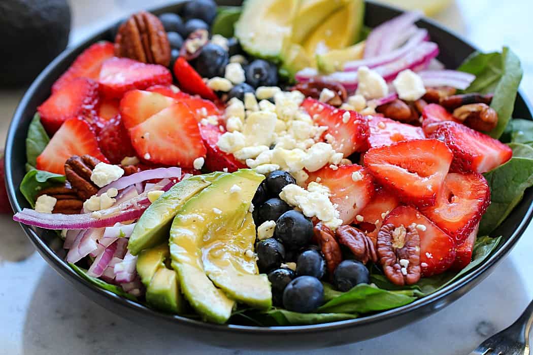 This is the most amazing Spinach Salad Recipe! Leaves of spinach topped with berries, avocado, feta cheese, walnuts and a homemade honey-garlic vinaigrette! #ad