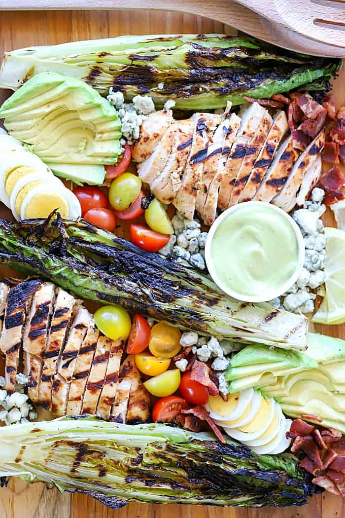 Deconstructed Cobb Salad on platter with marinated and grilled chicken, grilled romaine and other Cobb salad ingredients.