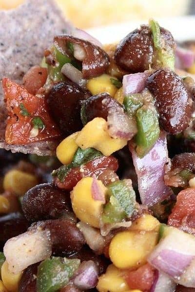 Close up shot of a Black Bean and Corn Salsa with a purple chip + 43 Healthy Snack Ideas