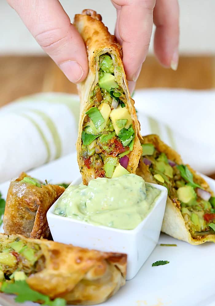 Photo of a sliced Egg Roll being dipped into an Avocado Dip. Yum!