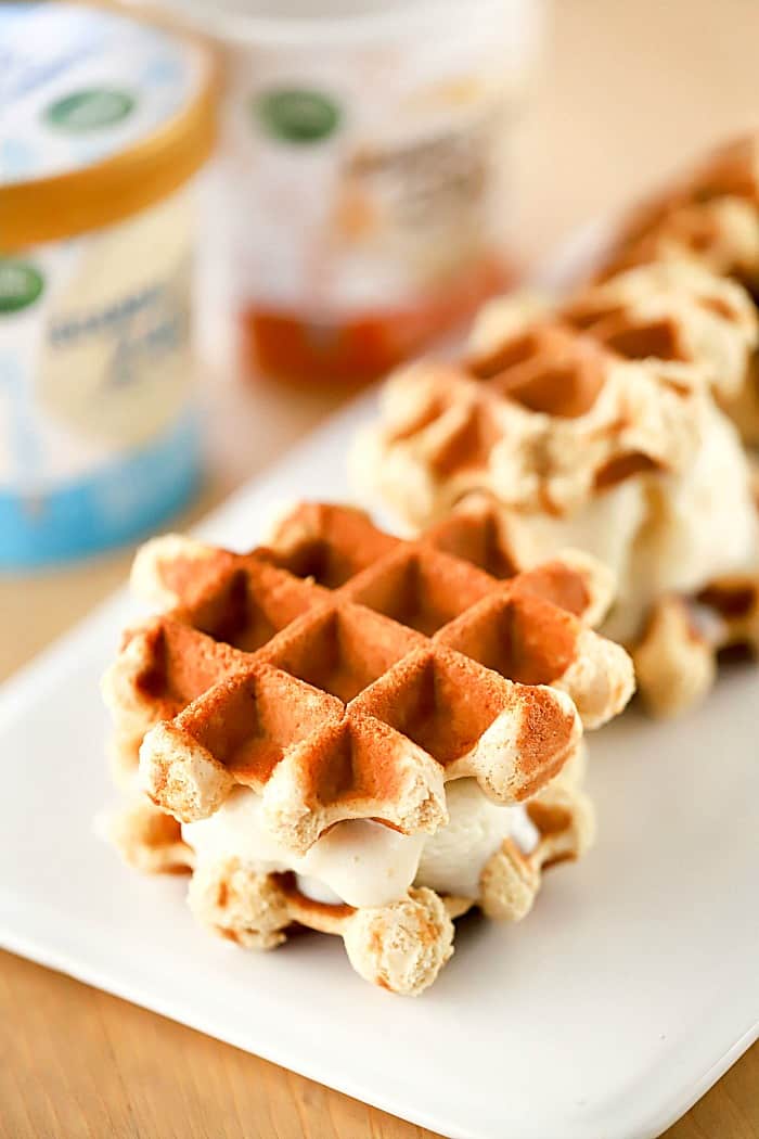 Ice Cream sandwiched between two waffle cookies on a plate with ice cream in the background.