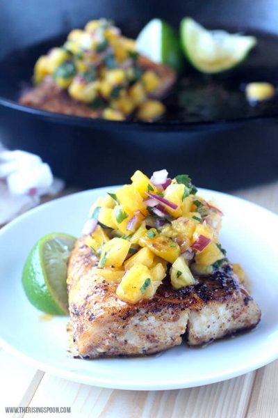 Pan-Seared Mahi-Mahi with Pineapple Salsa on a white plate with a slice of lime and another plate behind it.