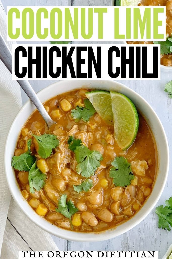 White bowl of chicken chili with a spoon and a lime on the side.