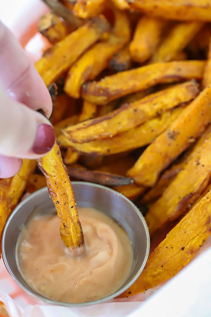 Sweet Potato Fry being dunked in fry sauce.