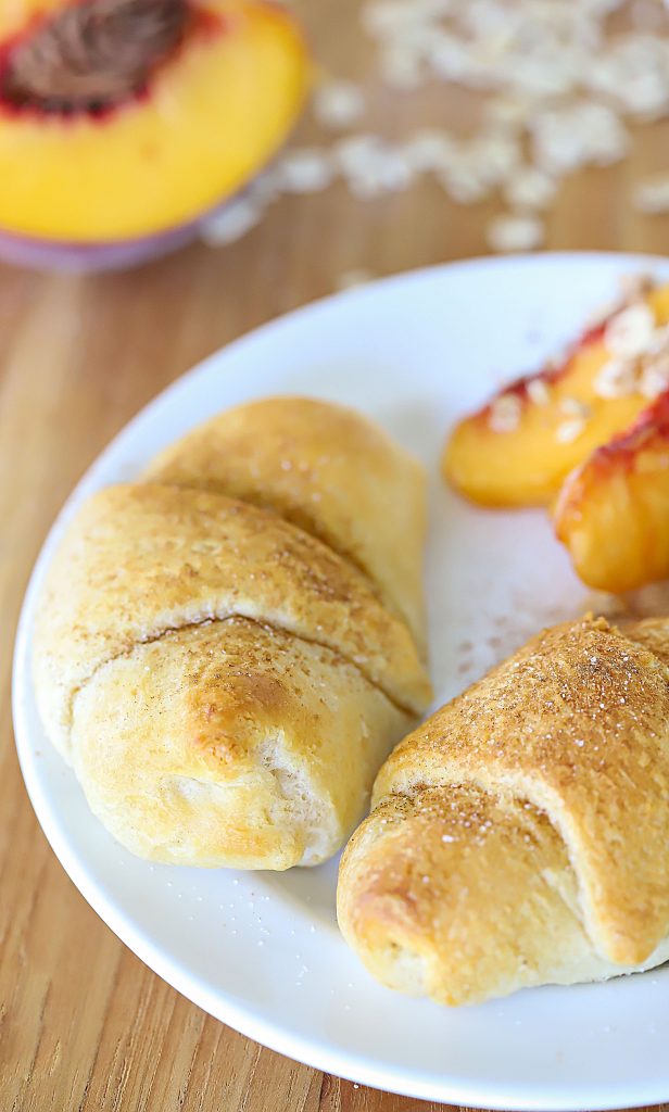 White plate with two filled crescent rolls and a side of peaches.